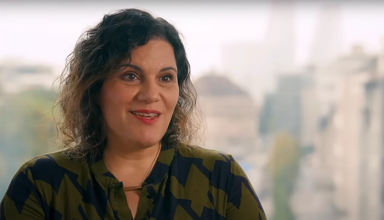 Smiling woman in an office setting, sharing insights. Discover opportunities with BeOne Careers.