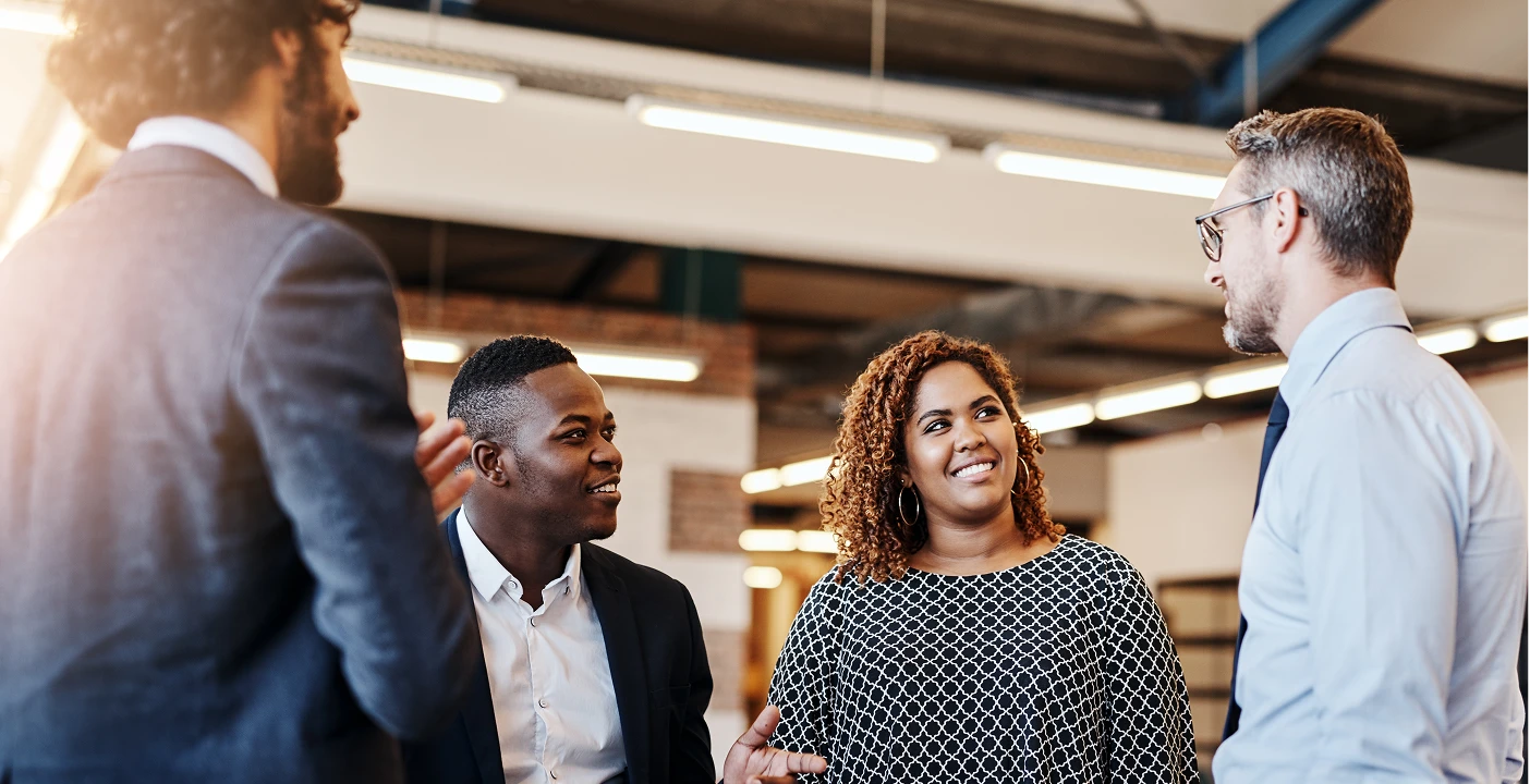Professionals engaging in a lively discussion in an office. Network and grow with BeOne Careers.